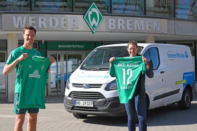 Bilder des Jahres 2020, Sport 04 April Sport Themen der Woche KW15 Sport Bilder des Tages STAYATHOME-TRIKOT: WERDER SPENDET 20.000 EURO FÜR INNERE MISSION 09.04.2020, Trainingsgelaende am wohninvest WESERSTADION,, Bremen, STAYATHOME-TRIKOT: WERDER SPENDET 20.000 EURO FÜR INNERE MISSION, Das STAYATHOMETRIKOT ist der Verkaufsschlager in Werders Online-Shop. Die Grün-Weißen und ihr Hauptsponsor WIESENHOF haben das Sondertrikot mit der Botschaft, die Menschenleben rettet, in den Verkauf gegeben und dürfen sich über einen riesigen Ansturm freuen. Einer der großen Gewinner der Aktion ist der Verein für Innere Mission in Bremen. Fünf Euro spendet Werder Bremen von jedem Trikot an den Verein, der sich um Menschen in Notsituationen kümmert. Der Ansturm sorgt nach nur wenigen Tagen für die erste 20.000-Euro-Spende an den Verein. Am Donnerstagmittag, übergab Werder-Profi Sebastian Langkamp das Geld an Katharina Kähler, Bereichsleiterin für die Wohnungslosenhilfe des Vereins. im Bild Spende übergeben: Sebastian Langkamp und Katharina Kähler