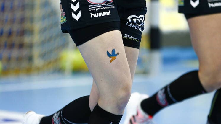 Bilder des Jahres 2022, Sport 04 April Sport Themen der Woche KW14 Sport Bilder des Tages Die Spielerinnen von HL Buchholz 08-Rosengarten tragen auf dem rechten Oberschenkel das Bild einer Friedenstaube in den Farben der ukrainischen Flagge, Fahne, Taube, Tattoo, Abziehbild, Ukrainekrieg, Krieg, Konflikt, Zeichen, Symbol. Frieden, Gedenken an die Opfer des Krieges in der Urkaine, 10.04.2022, Oldenburg (Deutschland), Handball, Bundesliga Frauen, VfL Oldenburg - HL Buchholz 08-Rosengarten