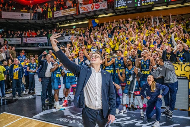 1. Basketball Bundesliga, easyCredit BBL, Saison 2025 2026, Herren, Hauptrunde, 13. Spieltag, 29.12.2025, RASTA Vechta - EWE Baskets Oldenburg Lazar Spasic (Head-Coach - EWE Baskets Oldenburg) beim Siegerselfie mit der Mannschaft und derren Fans Vechta RASTA Dome Niedersachsen Deutschland