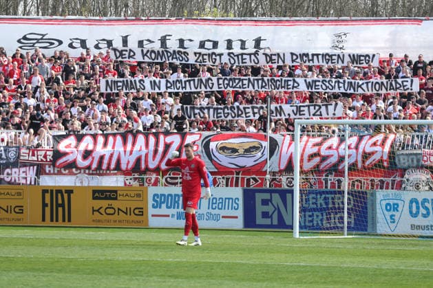 Fußball Regionalliga Nordost: 1. FC Lok Leipzig - Hallescher FC; 18.04.2026 Fanblock aus Halle mit Protest-Spruch für eine Regionalliga-Reform, Kompass-Modell. Spruchband. Fußball, Regionalliga Nordost, Saison 2025 2026, 30. Spieltag: 1. FC Lok Leipzig vs. Hallescher FC am 18.04.2026 im Bruno-Plache-Stadion, Leipzig. Copyright: xBEAUTIFULxSPORTS JanxKaeferx