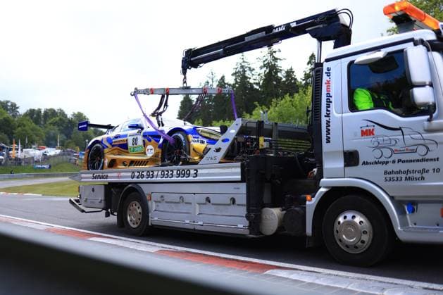Der Mercedes-AMG GT3 Fabian Schiller & Luca Stolz & Maro Engel & Maxime Martin (Mercedes-AMG Team RAVENOL) des Teams Mercedes-AMG Team RAVENOL wird nach einem Zwischenfall am Nürburgring auf einem Abschleppfahrzeug der Firma MK (Michael Krupp, Müsch) abtransportiert. Das Fahrzeug in der markanten blau-goldenen RAVENOL-Livery mit H&R-Sponsoring liegt gesichert auf der Ladefläche, während der Kranarm des LKW das Auto hält. Im Hintergrund sind die typischen grünen Bäume der Eifel sowie Streckenelemente des Nürburgrings zu erkennen. Mercedes-AMG GT3 80 von RAVENOL wird auf Abschleppwagen abtransportiert Copyright: xMichaelxGelhardtx