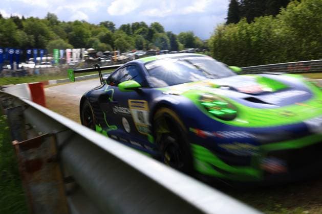 Ein Porsche 911 GT3 in der markanten dunkelblau-grünen Livery des Reiter Engineering Teams passiert mit hoher Geschwindigkeit eine Leitplanke auf der Nordschleife des Nürburgrings. Das Fahrzeug Rennfahrzeug trägt die Startnummer 91 und zeigt die typische Farbgebung des Teams mit auffälligen grünen Akzenten. Die Bewegungsunschärfe unterstreicht das hohe Tempo des Fahrzeugs beim ADAC RAVENOL 24h Nürburgring 2026. Porsche GT3 in Dunkel-Grün-Livery an der Leitplanke am Nürburgring Copyright: xMichaelxGelhardtx