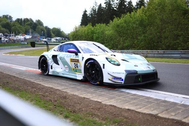 Der Porsche 911 GT3 R mit der Startnummer 24 von Lionspeed GP durchfährt eine Kurve auf dem Nürburgring. Das Fahrzeug Laurens Vanthoor & Laurin Heinrich & Ricardo Feller (Lionspeed GP) präsentiert sich in einer auffälligen weißen Livery mit mintgrünen Akzenten und dem Hauptsponsor Patentia. Die Aufnahme zeigt das Fahrzeug auf den charakteristischen rot-weißen Curbs der Strecke, im Hintergrund sind Leitplanken und die baumgesäumte Streckenumgebung der Eifel zu erkennen. Porsche 911 GT3 R 24 von Lionspeed GP auf dem Nürburgring Copyright: xMichaelxGelhardtx