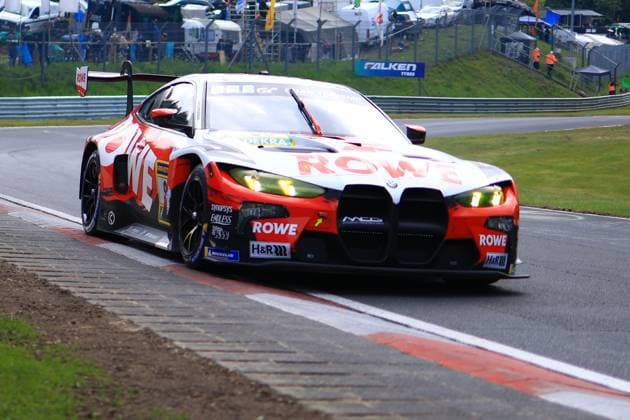 Das Augusto Farfus & Jordan Pepper & Kelvin van der Linde & Raffaele Marciello (ROWE RACING) von ROWE RACING durchfährt eine Kurve auf dem Nürburgring. Der BMW M4 GT3 präsentiert sich in der markanten rot-weißen ROWE-Livery mit leuchtenden gelb-grünen Scheinwerfern. Gut sichtbar sind die Sponsoren ROWE, H&R und Michelin auf der Karosserie. Im Hintergrund sind Zuschauerbereich und Fahrerlager erkennbar. BMW M4 GT3 1 von ROWE RACING auf dem Nürburgring Copyright: xMichaelxGelhardtx