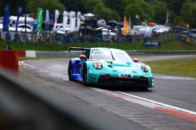 Der Klaus Bachler & Morris Schuring & Sven Müller & Tim Heinemann (Falken Motorsports) von Falken Motorsports nimmt eine Kurve am Nürburgring. Der Porsche 911 GT3 R präsentiert sich in der markanten türkis-blauen Falken-Livery mit H&R- und Falken-Sponsoring. Das Fahrzeug bewegt sich auf nassem Asphalt, im Hintergrund sind Fahnen und das Fahrerlager sichtbar. Falken Motorsports Porsche 911 GT3 R 44 am Nürburgring Copyright: xMichaelxGelhardtx
