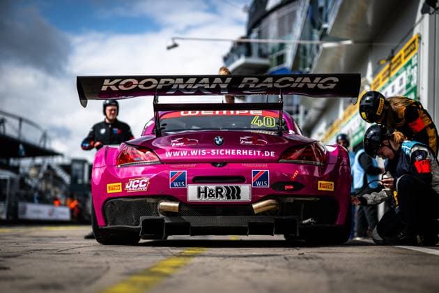 Der magentafarbene BMW Z4 GT3 mit der Startnummer 40 steht in der Boxengasse am Nürburgring. Mechaniker des W.I.S Racing Team powered by Koopman Racing arbeiten am Fahrzeug, während der markante Heckflügel mit dem Schriftzug Koopman Racing ins Auge sticht. Sponsoren wie H&R, Pirelli, JCC Racing und W.I.S. Sicherheit sind prominent auf der Karosserie platziert. Das Fahrzeug Frank Nikolaus & Michael Funke & Peter Posavac (W.I.S Racing Team powered by Koopman Racing) wird für den nächsten Stint vorbereitet. BMW Z4 GT3 40 von W.I.S Racing Team in der Box am Nürburgring Copyright: xMichaelxGelhardtx