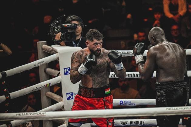 Intensiver Boxkampf zwischen Senad Gashi ( 120) und Peter Kadiru ( 129) in der SAP Arena Mannheim am 15.05.2026. Der tätowierte Boxer in roten Shorts führt offensiv an, während sein Gegner in defensiver Haltung reagiert. Ein Kameramann dokumentiert die Ringside-Action des Schwergewichtskampfs. Ringside, 15.05.2026, Mannheim, SAP Arena