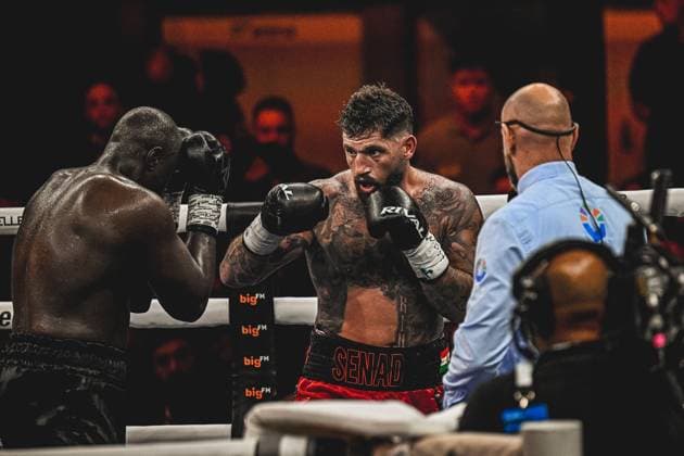 Senad Gashi und Peter Kadiru liefern sich einen packenden Schlagabtausch beim Boxevent Ringside – Night of the Heavyweights am 15.05.2026 in der SAP Arena Mannheim. Der tatowierte Gashi in roten Hosen zeigt aggressive Offensivbewegungen, während sein Gegner defensiv reagiert. Ein Ringrichter überwacht die Aktion konzentriert. Ringside, 15.05.2026, Mannheim, SAP Arena