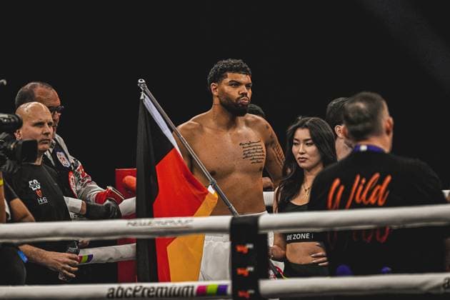 Emanuel Odiase (903; VIP) mit deutscher Flagge im Ring der SAP Arena, umgeben von Team und Offiziellen Ringside, 15.05.2026, Mannheim, SAP Arena