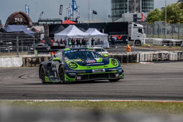 Der Porsche 911 GT3 R mit der Startnummer 48 von LOSCH Motorsport by BLACK FALCON durchfährt eine Kurve auf dem Nürburgring. Das in dunklem Grün mit auffälligen Neongrün-Akzenten gehaltene Fahrzeug Daan Arrow & Dylan Pereira & Patrick Assenheimer & Tobias Müller (48 LOSCH Motorsport by BLACK FALCON) trägt die Sponsoren Liqui-Moly, H&R, Goodyear und Fanatec sowie das Gran Turismo-Logo auf der Frontpartie. Im Hintergrund sind die Infrastruktur des Fahrerlagers, Zelte und Trucks zu sehen. Porsche 911 GT3 48 von LOSCH Motorsport by BLACK FALCON am Nürburgring Copyright: xMichaelxSchäferx
