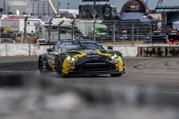 Der schwarz-gelbe Aston Martin Vantage GT3 mit der Startnummer 35 von Walkenhorst Motorsport durchfährt die Boxengassenausfahrt am Nürburgring. Das Fahrzeug trägt die Sponsoren natural elements, H&R, Pirelli und RAVENOL und ist mit eingeschalteten Scheinwerfern unterwegs. Im Hintergrund sind Streckenposten, Absperrungen und Teamtrucks des Fahrerlagers sichtbar. Felipe Fernandez Laser (natural elements by Walkenhorst Motorsport) Aston Martin Vantage GT3 35 von Walkenhorst Motorsport am Nürburgring Copyright: xMichaelxSchäferx
