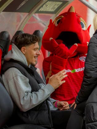 Ingolstadt, Deutschland 16. Mai 2026: 3. Liga - 2025 2026 - Sp. 38 - FC Ingolstadt 04 gegen SV Waldhof Mannheim Im Bild: v.li. der verletzte Dennis Kaygin (FCI) in zivil mit Maskottchen Schanzi auf der Bank. DFB regulations prohibit any use of photographs as image sequences and or quasi-video Audi Sportpark Bayern Copyright: xFotostandx xSchäferx