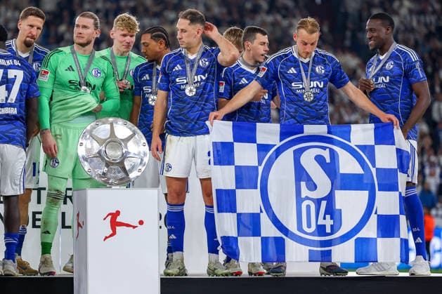 17.05.2026, Fußball, FC Schalke 04 - Eintracht Braunschweig, 34. Spieltag, 2. Fußball Bundesliga, Veltins-Arena Gelsenkirchen, Saison 2025 2026: Schalke 04 ist Meister der 2. Bundesliga. Die Mannschaft gewinnt die Meisterschaft und steht jubelnd auf dem Spielfeld. Freude und Emotionen nach dem Sieg. Timo Becker (Schalke04 05) mit der Fahne auf dem Siegerehrungspodest DFB regulations prohibit any use of photographs as image sequences and or quasi-video. Nordrhein-Westfalen Deutschland