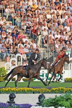 Richard Vogel und Luciana Diniz im Tempo gemeinsam in Bond-Stunt-Feeling über die Hindernisse, Konzert Pferd & Sinfonie, Rahmenprogramm, Motto des Abends: James Bond, Weltfest des Pferdesports, World Equestrian Festival, TSCHIO Aachen 2026, TSCHIO statt CHIO 2026, Aachener Soers, 22. bis 24. Mai 2026, Reitsport, 23.05.2026, Aachen Aachener Soers Deutschland