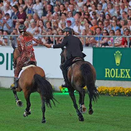 Richard Vogel und Luciana Diniz im Tempo gemeinsam in Bond-Stunt-Feeling über die Hindernisse, Konzert Pferd & Sinfonie, Rahmenprogramm, Motto des Abends: James Bond, Weltfest des Pferdesports, World Equestrian Festival, TSCHIO Aachen 2026, TSCHIO statt CHIO 2026, Aachener Soers, 22. bis 24. Mai 2026, Reitsport, 23.05.2026, Aachen Aachener Soers Deutschland