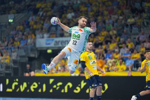 Ein Spieler des SC Magdeburg ( 22, weißes Trikot) zieht in der SAP Arena zum Sprungwurf hoch, während Jannik Kohlbacher ( 80, Rhein Neckar Löwen) im Hintergrund zu sehen ist. Das Duell zwischen den Rhein Neckar Löwen und dem SC Magdeburg in der DAIKIN HBL sorgt für packende Szenen vor ausverkauftem Haus. SC Magdeburg 22 im Sprungwurf gegen Rhein Neckar Löwen in der SAP Arena