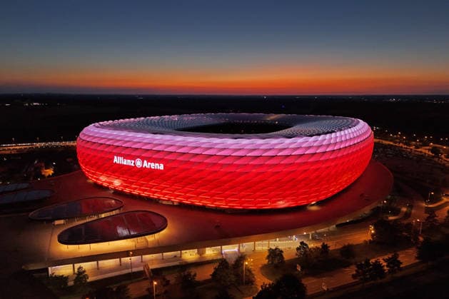 ALLIANZ ARENA leuchtet bei Nacht.Abenddaemmerung, Heimspielstaette des FC Bayern Muenchen, Fussballstadion,Stadion,Uebersicht,Totale.