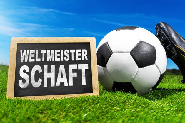 Germany - May 27, 2026: PHOTO MONTAGE, stock photo for the 2026 FIFA World Cup, WM, Weltmeisterschaft, Fussball A soccer ball, red and yellow referee cards, and a whistle lie on green field turf next to a sign bearing the words World Cup.