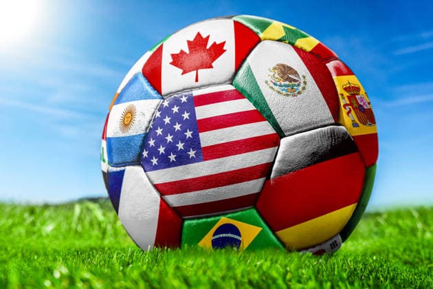 Germany - May 27, 2026: PHOTO MONTAGE, stock photo for the 2026 FIFA World Cup, WM, Weltmeisterschaft, Fussball - A soccer ball with various national flags on the field under a blue sky. The flags shown include those of the United States, Mexico, Canada, Spain, Brazil, and Argentina.