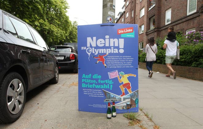 Zwei Piccolo-Flaschen stehen vor einem Plakat der Partei Die Linke, mit dem sie sich gegen eine Bewerbung Hamburgs für die Austragung von Olympischen Spielen und Paralympics positioniert und dazu aufruft, beim Bürgerschaftsreferendum am 31. Mai mit Nein zu stimmen. Barmbek Hamburg