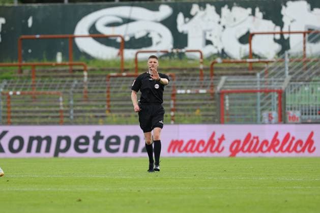 01.08.26, GER, Regionalliga Nord, Fussball, 1. Spieltag, Saison 2026 2027, Dietmar-Scholze-Stadion an der Lohmuehle, VfB Luebeck vs SC Weiche Flensburg Einzelaktion Aktion Ganze Figur Einzeln Freisteller Schiedsrichter Kevin Behrens gibt Handzeichen. Bandenwerbung Kompetenz macht glücklich Foto nordphoto GmbH Tauchnitz Luebeck Dietmar-Scholze-Stadion an der Lohmuehle SH Germany Copyright: xnordphotoxGmbHx xTauchnitzx