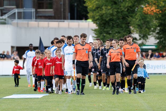 Davina Lutz (Schiedsrichter:in), Kevin Rösch (Schiedsrichterassistent:in) und Christoph Stühler (Schiedsrichterassistent:in) führen die Mannschaften aufs Spielfeld beim Spiel zwischen TSV Landsberg v FV Illertissen 1921, Fussball, Herren, Regionalliga Bayern, 2026 2027, 3.Spieltag am 07.08.2026 in Landsberg am Lech, Sportpark. Bayern Deutschland