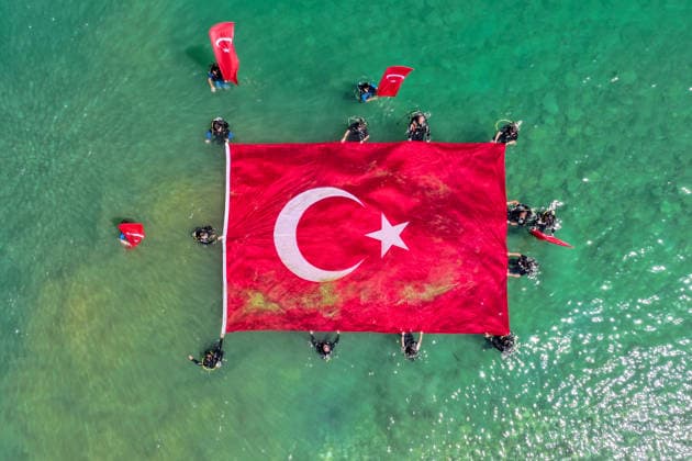 12th Van Sea Water Sports Festival kicks off on Lake Van VAN, TURKIYE - AUGUST 08: An aerial view of divers unfurling a large Turkish flag as participants and athletes taking part in the 12th Van Sea Water Sports Festival held at the Edremit-Gebze Water Sports Center on the shores of Lake Van in Van, Turkiye, on August 08, 2026. Organized to promote Lake Van and boost local tourism, the two-day event features Beach volleyball, Beachvolleyball and handball matches, flyboard demonstrations, canoeing, rowing, dragon boat races, and various recreational activities. Ozkan Bilgin Anadolu Van Turkey. Editorial use only. Please get in touch for any other usage. Copyright: x2026xAnadoluxOzkanxBilginx