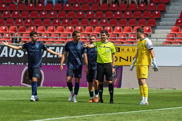 Fußball I Herren I Saison 2026-2027 I Regionalliga I 4. Spieltag I Hallescher FC - Chemnitzer FC I 09.08.2026 Schiedsrichter Christoph Beblik (2.v.r.) zeigt auf den Elfmeterpunkt, Chemnitzer Spieler stehen um ihn herum Halle (Saale) Leuna-Chemie-Stadion Sachsen-Anhalt Deutschland Copyright: xLobeca InesxHähnelx