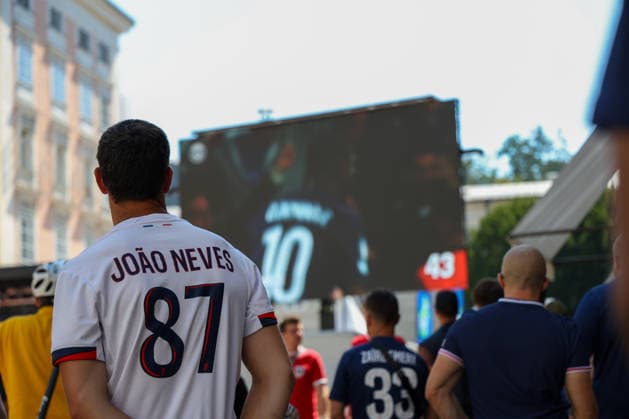 Österreich: Fußball UEFA Super Cup 2026, Finale, Paris Saint-Germain vs Aston Villa FC, Salzburg: Ein Fan trägt ein Trikot von Joao Neves (Paris Saint-Germain) und verfolgt gemeinsam mit weiteren Zuschauern das UEFA Super Cup Finale 2026 zwischen Paris Saint-Germain und Aston Villa FC auf einer Großbildleinwand im Fan Festival in der Salzburger Innenstadt. Copyright: xAymanxAlahmedx