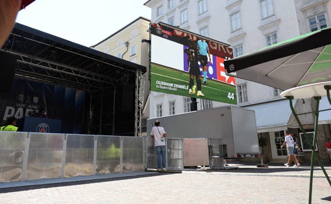 Österreich: Fußball UEFA Super Cup 2026, Finale, Paris Saint-Germain vs Aston Villa FC, Salzburg: Fan Festival von Paris Saint-Germain in der Salzburger Innenstadt vor dem UEFA Super Cup Finale 2026 zwischen Paris Saint-Germain und Aston Villa FC. Eine Großbildleinwand zeigt Spielszenen von Ousmane DembÃ lÃ , während Besucher das Programm im Fan-Areal verfolgen. Copyright: xAymanxAlahmedx