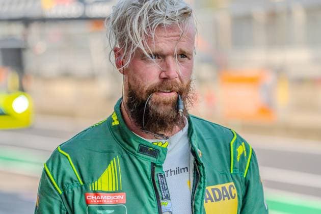 Sport Bilder des Tages Nicki Thiim vom Comtoyou Racing steht in seinem grün-neongelben Rennoverall mit Headset am Nürburgring in der Boxengasse. Auf dem Overall sind die Logos von Champion Lubricants und ADAC sichtbar. Nicki Thiim (Comtoyou Racing) am Nürburgring im Porträt Copyright: xMichaelxSchäferx