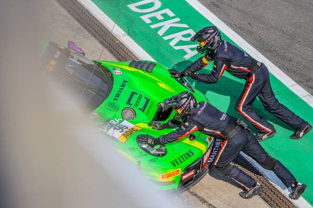 Sport Bilder des Tages Zwei Mechaniker von Manthey Racing schieben den neongrünen Porsche 911 GT3 R 90 mit Ricardo Feller am Steuer in der Boxengasse des Nürburgrings. Die Vogelperspektive zeigt den Boxenstopp-Moment mit DEKRA-Schriftzug auf dem Asphalt. Porsche 911 GT3 R 90 von Manthey Racing beim Boxenstopp am Nürburgring Copyright: xMichaelxSchäferx