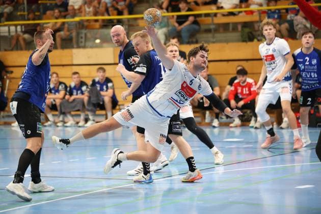Rasmus Houmøller ( 6; VfL Lübeck-Schwartau) zieht dynamisch zum Wurf ab und wird dabei von Kristoffer Jessen ( 11; Grindstedt GIF) bedrängt. Einar Nickelsen ( 42; VfL Lübeck-Schwartau) steht im Hintergrund bereit, während der Ball bereits in der Wurfbewegung ist. Rasmus Houmøller ( 6; VfL Lübeck-Schwartau) beim Wurf gegen Grindstedt GIF