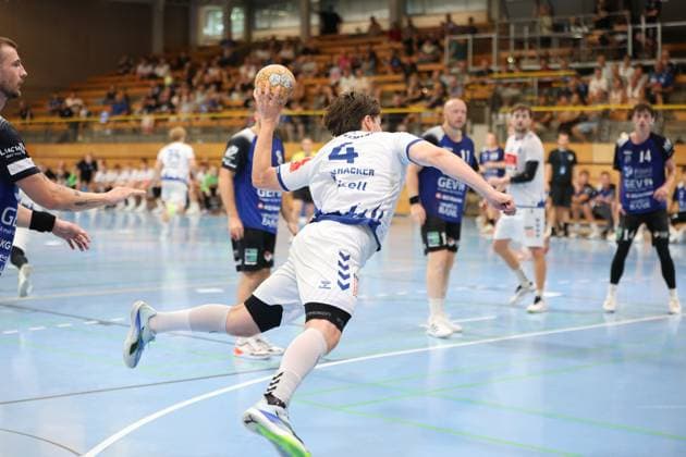 Paul Holzhacker ( 4; VfL Lübeck-Schwartau) zieht in einer dynamischen Sprungwurfbewegung ab, den Ball bereits in der Wurfhand. Mehrere Spieler von Grindstedt GIF verfolgen die Aktion im Hintergrund. Paul Holzhacker ( 4; VfL Lübeck-Schwartau) beim Sprungwurf