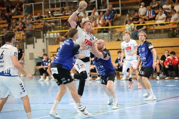 Ole Hagedorn von VfL Lübeck-Schwartau springt zum Wurf und wird dabei von Kristoffer Jessen ( 11; Grindstedt GIF) unter Druck gesetzt. Im Hintergrund sind weitere Spieler beider Teams sowie die gut gefüllten Zuschauerränge der Hansehalle in Lübeck zu sehen. Ole Hagedorn (VfL Lübeck-Schwartau) zieht ab gegen Grindstedt GIF
