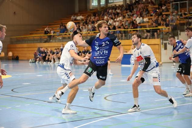 Rune Overlund ( 25; Grindstedt GIF) springt mit dem Ball in der Hand zum Wurf ab, während Rasmus Houmøller ( 6; VfL Lübeck-Schwartau) und ein weiterer Lübecker Abwehrspieler ihn unter Druck setzen. Maximilian Botta ( 19; VfL Lübeck-Schwartau) sichert im Hintergrund die Abwehr, vor voll besetzten Zuschauerrängen in der Hansehalle Lübeck. Rune Overlund ( 25; Grindstedt GIF) im Sprungwurf gegen VfL Lübeck-Schwartau