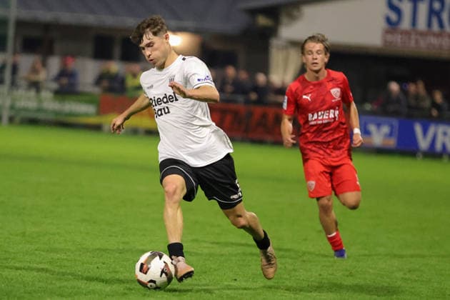 18.09.2026, Fussball, Herren, Saison 2026 2027, Regionalliga Bayern, 10. Spieltag: TSV Buchbach - FC Schweinfurt 05 Lauris Bausenwein (FC Schweinfurt 05, 21) vor Philipp Zimmerer (TSV Buchbach, 19) Buchbach SMR-Arena Bayern Deutschland