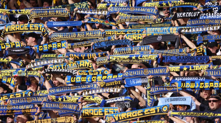19.09.2026, Fussball, Herren, 3. Liga, Saison 2026 2027, 1. FC Saarbrücken - SG Sonnenhof Großaspach, Fans des 1. FC Saarbrücken halten ihre Schals hoch und singen gemeinsam das Vereinslied Saarbrücken Ludwigsparkstadion Saarland Deutschland Copyright: xFabianxKleerx