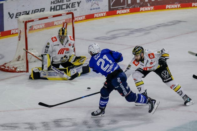 25.09.2026, xhettx, Eishockey Penny DEL, Adler Mannheim - Krefeld Pinguine v.l. Kris Bennett (Adler Mannheim, 21) schießt auf das Tor von Juha Jatkola (Krefeld Pinguine, 32)