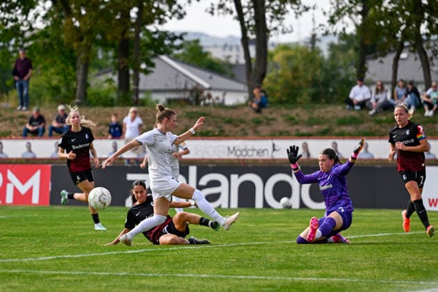 25.09.2026, Fußball, 1. HauptrunDFB-Pokal Frauen 2026 2027, SG 99 Andernach - SC Freiburg Ilayda Acikgöz (am Boden, SC Freiburg) bekommt im letzten Moment die Fußspitze an den Ball. Stürmerin Carolin Schraa (7 SG 99 Andernach) stand bereits zum Schuss bereit. Torhüterin Lorena Barth ging auch von einem Schuss aufs Tor aus.