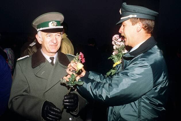 Westberliner Polizist steckt einem Offizier der Grenztruppen der DDR in der Nacht des Mauerfalls eine Blume ins Knopfloch