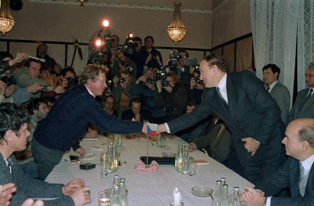 Playwrite and the representative of Civic Forum Vaclav Havel (L) shakes hands with Secretary of the government Marian Calfa. Other politicians, actors and the singer Michael Kocab are looking on in Prague, Czechoslovakia on Nov. 26, 1989. 