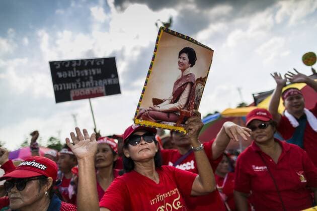 May 10, 2014 - Bangkok, Bangkok, Thailand - A supporter of Yingluck Shinawatra holds up a photo of the ousted Prime Minister at a rally in Bangkok. Thousands of Thai Red Shirts, members of the United Front for Democracy Against Dictatorship (UDD), members of the ruling Pheu Thai party and supporters of the government of ousted Prime Minister Yingluck Shinawatra are rallying on Aksa Road in the Bangkok suburbs. The government was ousted by a court ruling earlier in the week that deposed Yingluck because the judges said she acted unconstitutionally in a personnel matter early in her administration. Thailand now has no functioning government. Red Shirt leaders said at the rally Saturday that any attempt to impose an unelected government on Thailand could spark a civil war. This is the third consecutive popularly elected UDD supported government ousted by the courts in less than 10 years. - ZUMAk94