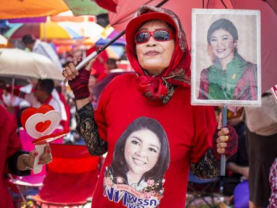 May 10, 2014 - Bangkok, Bangkok, Thailand - A supporter of Yingluck Shinawatra, carrying a photo of Yingluck and wearing a tee shirt with Yingluck s picture on it at a Red Shirt rally in Bangkok. Thousands of Thai Red Shirts, members of the United Front for Democracy Against Dictatorship (UDD), members of the ruling Pheu Thai party and supporters of the government of ousted Prime Minister Yingluck Shinawatra are rallying on Aksa Road in the Bangkok suburbs. The government was ousted by a court ruling earlier in the week that deposed Yingluck because the judges said she acted unconstitutionally in a personnel matter early in her administration. Thailand now has no functioning government. Red Shirt leaders said at the rally Saturday that any attempt to impose an unelected government on Thailand could spark a civil war. This is the third consecutive popularly elected UDD supported governmen - ZUMAk94