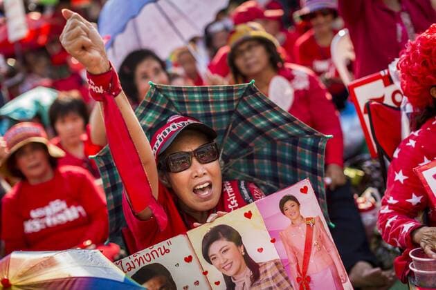 May 10, 2014 - Bangkok, Bangkok, Thailand - A supporter of Yingluck Shinawatra, carrying photos of Yingluck at a Red Shirt rally in Bangkok. Thousands of Thai Red Shirts, members of the United Front for Democracy Against Dictatorship (UDD), members of the ruling Pheu Thai party and supporters of the government of ousted Prime Minister Yingluck Shinawatra are rallying on Aksa Road in the Bangkok suburbs. The government was ousted by a court ruling earlier in the week that deposed Yingluck because the judges said she acted unconstitutionally in a personnel matter early in her administration. Thailand now has no functioning government. Red Shirt leaders said at the rally Saturday that any attempt to impose an unelected government on Thailand could spark a civil war. This is the third consecutive popularly elected UDD supported government ousted by the courts in less than 10 years. - ZUMAk94