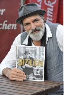 Andreas Hoppe (Schauspieler) 10 17 thg Andreas Hoppe am 12. Oktober 2017 w hrend der Frankfurter Buchmesse Messe Literaturmesse Literatur Frankfurt Main Deutschland deutsch deutscher Mann Schauspiel Film TV Fernsehen german actor hoch halb sitzend Kochbuch Buch Buchtitel haltend Sizilien