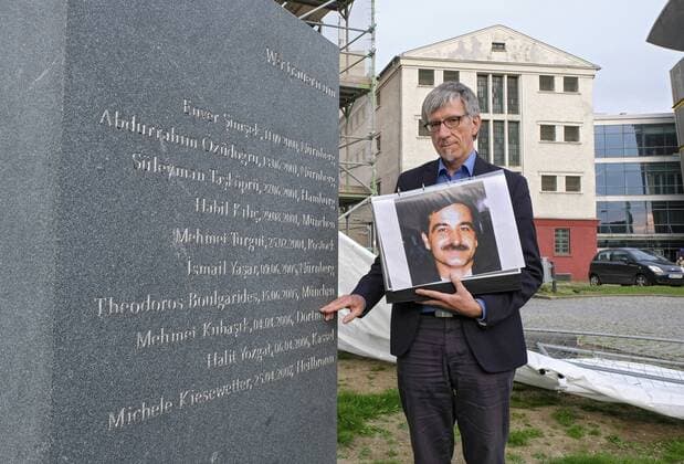 Probe von einem Stadtrundgang zum Thema Rechtsextremismus in Dortmund am 27.05.19 fuer den evangelischen Kirchentag (Foto: Der evangelische Pfarrer Friedrich Stiller mit einem Foto des Dortmunder NSU-Opfers Mehmet Kubasik am Mahnmahl fuer die Opfer der NSU-Morde vor dem ehemaligen Nazi-Gefaengnis Steinwache (im Hintergrund)). Es ist eine Station von acht Stationen des Stadtrundgangs beim evangelischen Kirchentag in Dortmund vom 19. bis 23. Juni 2019. Der Kirchentag bietet alternative Stadtrundgaenge zum Thema Rechtsextremismus an, um zu zeigen: Eine Stadt wehrt sich. (Siehe epd-Bericht vom 12.06.2019) Stadtrundgang zum Thema Rechtsextremismus in Dortmund