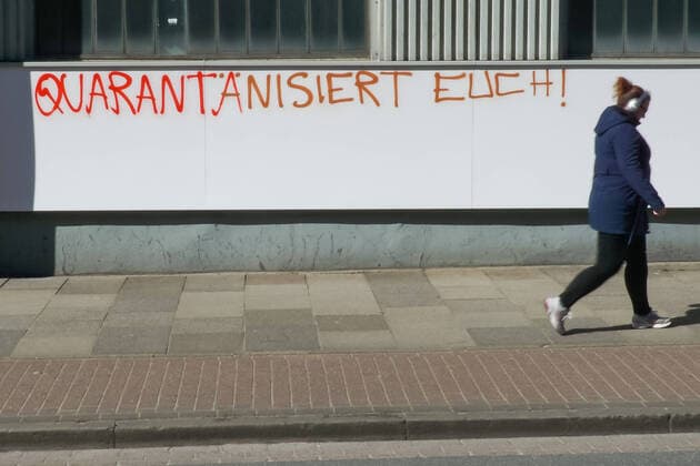 Bilder des Jahres 2020, News 03 März News Bilder des Tages Zur Eindämmung des Coronavirus wurden Geschäftsschließungen angeordnet und werden Ausgangssperren diskutiert, das Foto zeigt eine Fußgängerin vor einem Graffiti, Schriftzug an einem gebäude mit der Aufschrift: Quarantänisiert Euch, 22.03.2020, Bremen (Deutschland), News, Feature, Coronavirus Bremen