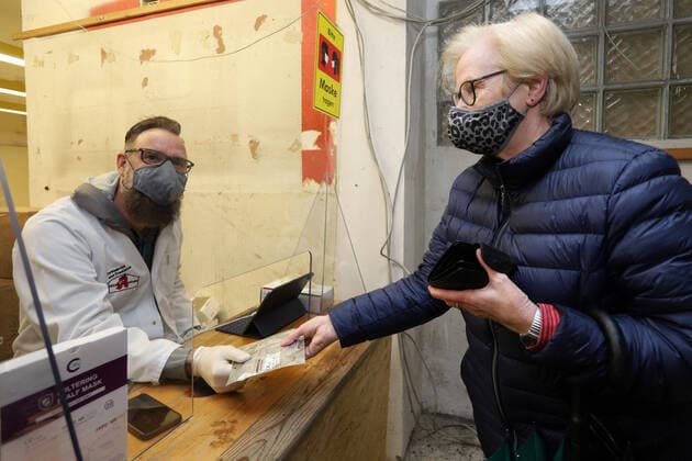 Bilder des Jahres 2020, News 12 Dezember News Bilder des Tages FFP2 Maskenausgabe, eine Frau holt sich die kostenlosen FFP2 Masken in der Apotheke, die Glueckauf Apotheke in Niederschelden hat einen Extra Raum neben der eigentlichen Apotheke wo die Masken an die besonders gefaerhdeten Personen ausgegeben werden, der Inhaber der Glueckauf Apotheke Henning Schweisfurth li. uebergibt die FFP2 Masken an eine Frau FFP2 Maskenausgabe, Coronavirus am 15.12.2020 in Siegen Deutschland.