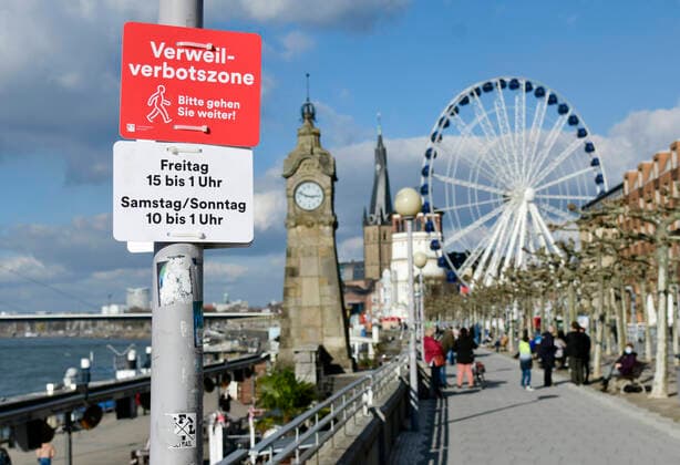 Bilder des Jahres 2021, News 02 Februar News Themen der Woche KW08 News Bilder des Tages F95 - H96 Düsseldorf, NRW 26.2.2021, Corona, Bitte gehen Sie weiter: Aufgrund der Menschenansammlungen am vergangenen Wochenende hat die Stadt Düsseldorf ein Verweilverbot für die Rheinuferpromenade in der Altstadt festgelegt. Dieses gilt an Freitagen von 15:00 Uhr bis 1:00 Uhr und an Sa So. von 10:00 bis 1:00 Uhr. Noch ist es 14:50 am Freitag und Menschen nutzen die Zeit auf den Parkbänken.